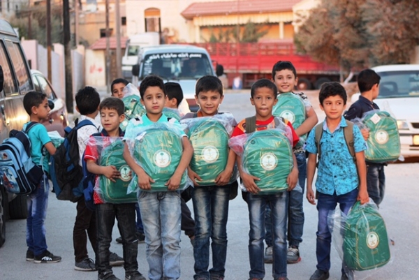 طلاب سوريون في أربد فرحين بالحقائب المدرسية المقدمة لهم من الحملة السعودية.