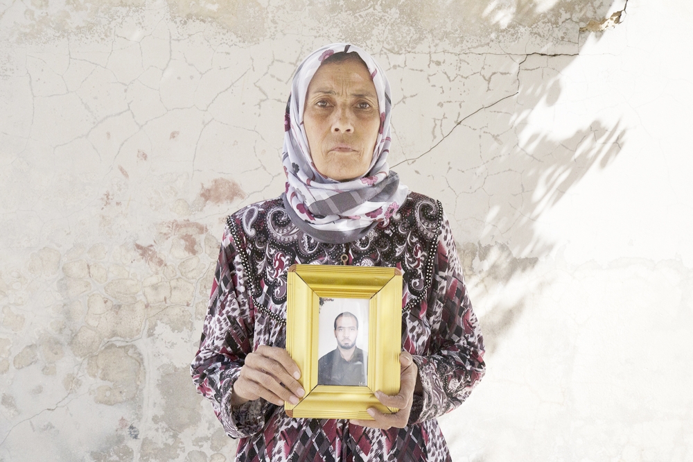 This picture released on Wednesday, Oct. 26, 2016 by the New York-based group Human Rights Watch, shows Zakia Hassan holds a photo of her son, Ibrahim Hammud, 35, who detonated an explosive device when he stepped on a mattress as he returned to his house in Manbij, Syria. Homemade landmines planted by the Islamic State group have killed and injured hundreds of civilians, including dozens of children, in the town of Manbij in northern Syria, Human Rights Watch says. (Ole Solvang, Human Rights Watch via AP)