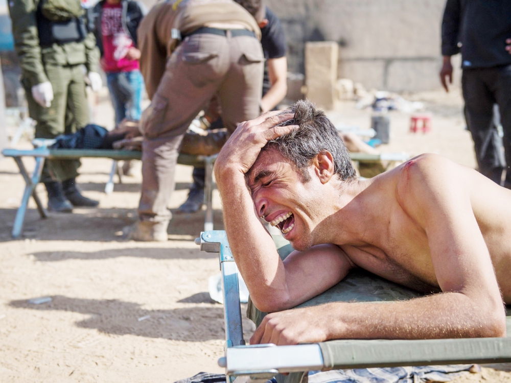 Mosul resident Hassan suffering shrapnel wounds to his upper body cries out for his son, 18-month-old Jassem being treated for head injuries at an Iraqi Special Forces 2nd division open air field clinic in the Samah neighbourhood of Mosul on November 17, 2016. Iraqi forces have broken into jihadist-held Mosul and recaptured neighbourhoods inside the city, but a month into their offensive, there are still weeks or more of potentially heavy fighting ahead. The medical point saw a spike in patients today with dozens coming through in a few hours among them several children and 5 fatalities. / AFP / Odd ANDERSEN
