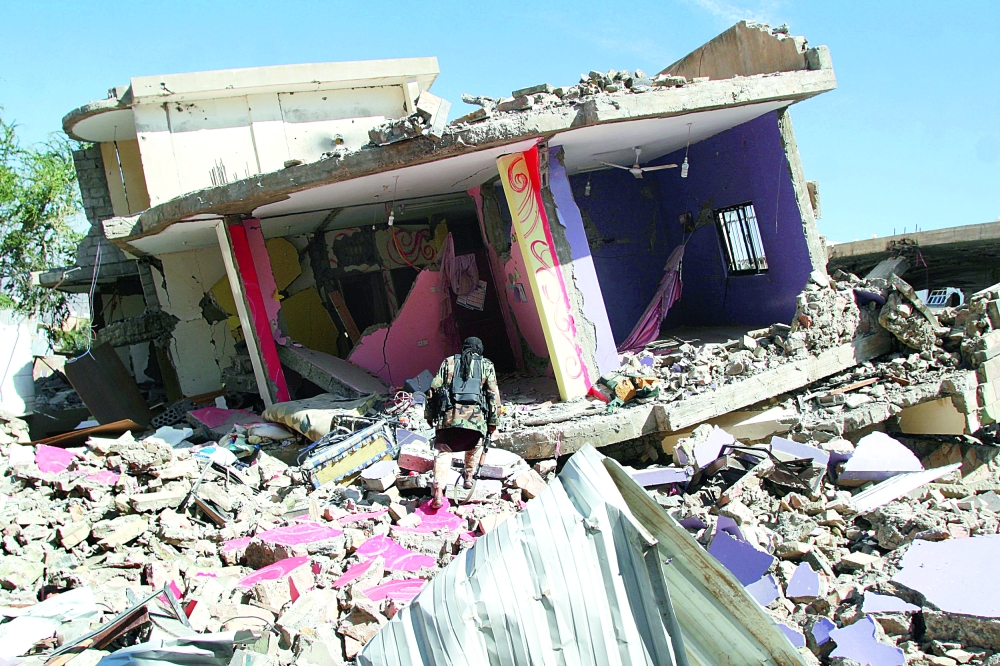 مقاتل من المقاومة يعاين أنقاض منزل نسفته ميليشيا الحوثي في جنوب غرب تعز أمس الأول. (رويترز)