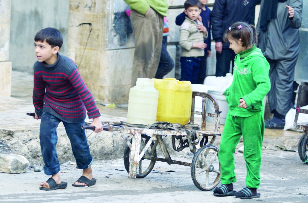 طفلان يحملان الماء في مدينة حلب التي لا تزال تشهد قصفا جويا من قبل طيران النظام السوري وروسيا. (أ.ف.ب)