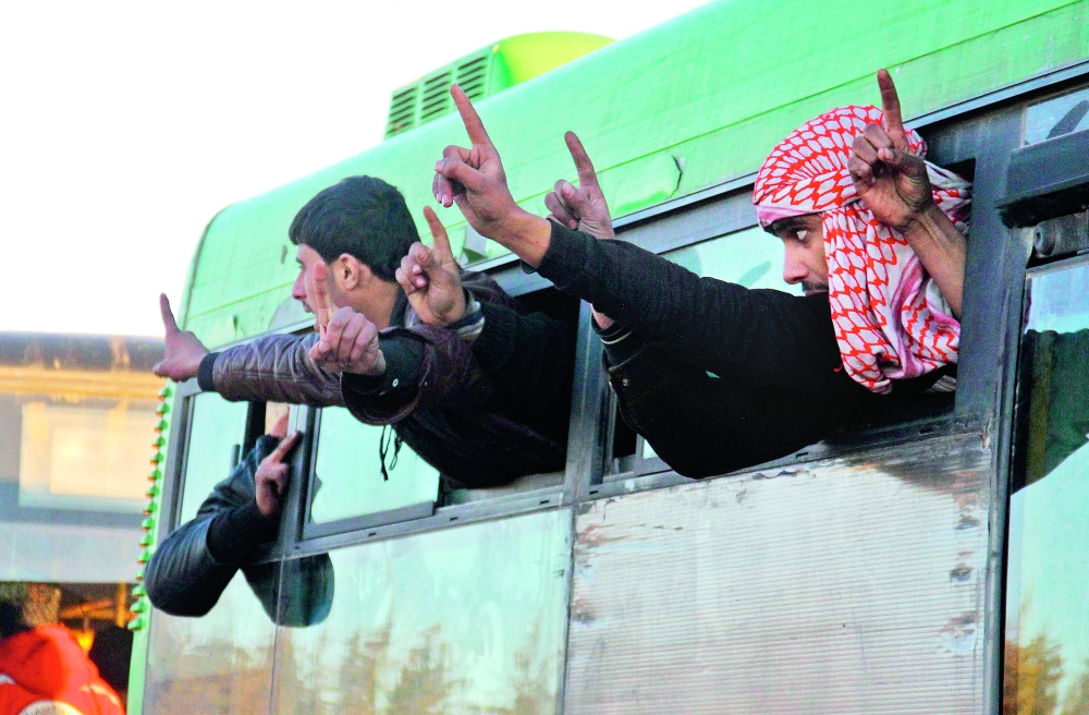 Syrians, who were evacuated from rebel-held neighbourhoods in the embattled city of Aleppo, gesture as they arrive in the opposition-controlled Khan al-Aassal region, west of the city, on December 15, 2016, the first stop on their trip, where humanitarian groups will transport the civilians to temporary camps on the outskirts of Idlib and the wounded to field hospitals. A convoy carrying the first evacuees from rebel-held parts of Syria's Aleppo arrived in opposition territory west of the city on Thursday, a doctor there and a monitor said.  / AFP / Omar haj kadour
