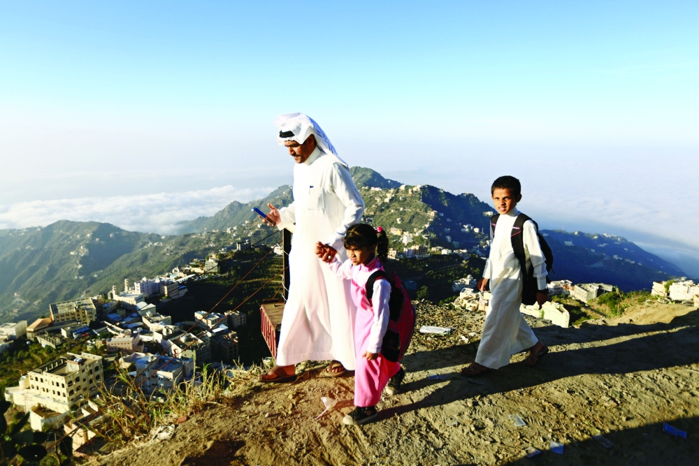 Saudi man Yazid al-Fefi walks with his children as they make their way to their schools through Fifa Mountain, in Jazan, south of Saudi Arabia, December 15, 2016. Picture take December 15, 2016. REUTERS/Mohamed Al Hwaity