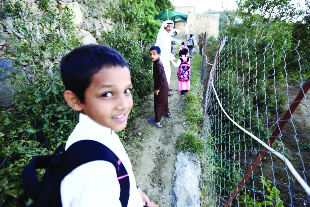 Saudi man Yazid al-Fefi walks with his children as they make their way to their schools through Fifa Mountain, in Jazan, south of Saudi Arabia, December 15, 2016. Picture take December 15, 2016. REUTERS/Mohamed Al Hwaity