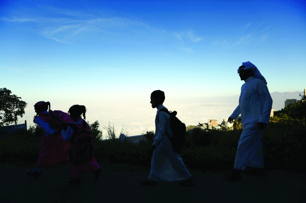 Saudi man Yazid al-Fefi walks with his children as they make their way to their schools through Fifa Mountain, in Jazan, south of Saudi Arabia, December 15, 2016. Picture take December 15, 2016. REUTERS/Mohamed Al Hwaity