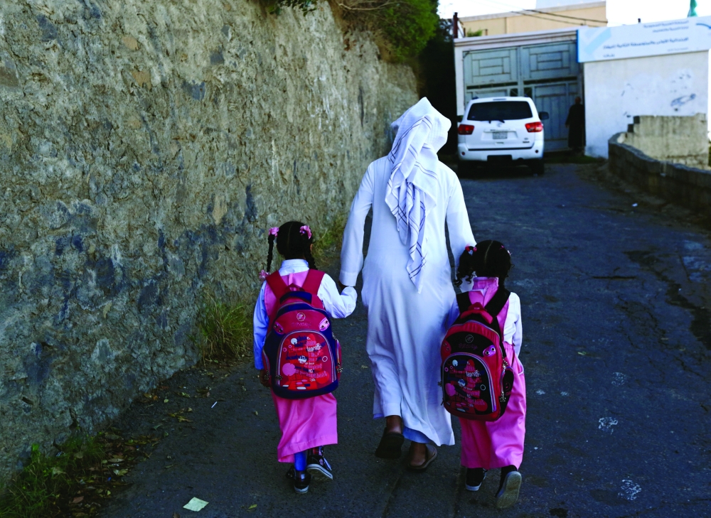 Saudi man Yazid al-Fefi holds the hands of his daughters as they arrive to their school after making their way through Fifa Mountain, in Jazan, south of Saudi Arabia, December 15, 2016. Picture take December 15, 2016. REUTERS/Mohamed Al Hwaity