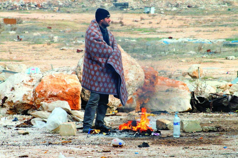 حد المدنيين في حلب الشرقية يشعل نارا تقيه برد الشتاء بانتظار وصول الحافلات للمغادرة. (أ. ب)