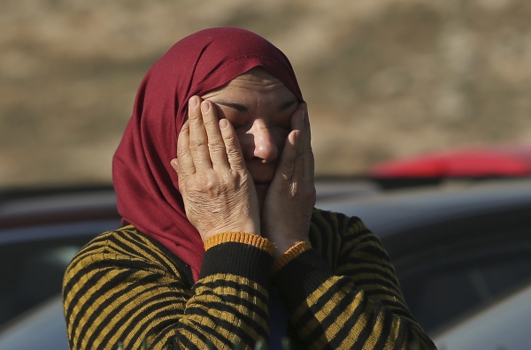 A Syrian woman waits for other family members to cross into Turkey at the Cilvegozu border gate with Syria, near Hatay, southeastern Turkey, Monday, Dec, 19, 2016. United Nations' Security Council on Monday approved the deployment of U.N. monitors to the Syrian city of Aleppo as the evacuation of fighters and civilians from the last remaining opposition stronghold resumed after days of delays. (AP Photo/Emrah Gurel)