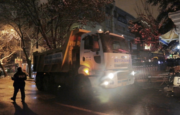 A Turkish police officer walks at the entrance of popular Tunali Hilmi Street, closed with trucks and buses against possible car bomb attacks, in Ankara, Turkey, early Sunday, Jan. 1, 2017. An assailant believed to have been dressed in a Santa Claus costume and armed with a long-barrelled weapon, opened fire at a nightclub in Istanbul's Ortakoy district during New Year's celebrations, killing dozens of people and wounding dozens of others in what the province's governor described as a terror attack.(AP Photo/Burhan Ozbilici)