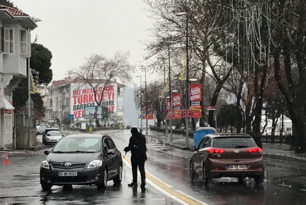 A Turkish anti riot police officer stops a car near the Reina night club , one of the Istanbul's most exclusive party spots, as forensic officers work inside early on January 1, 2017 after at least one gunmen went on a shooting rampage during New Year's Eve celebrations.  Thirty-nine people, including many foreigners, were killed when a gunman reportedly dressed as Santa Claus stormed an Istanbul nightclub as revellers were celebrating the New Year, the latest carnage to rock Turkey after a bloody 2016. / AFP / GURCAN OZTURK
