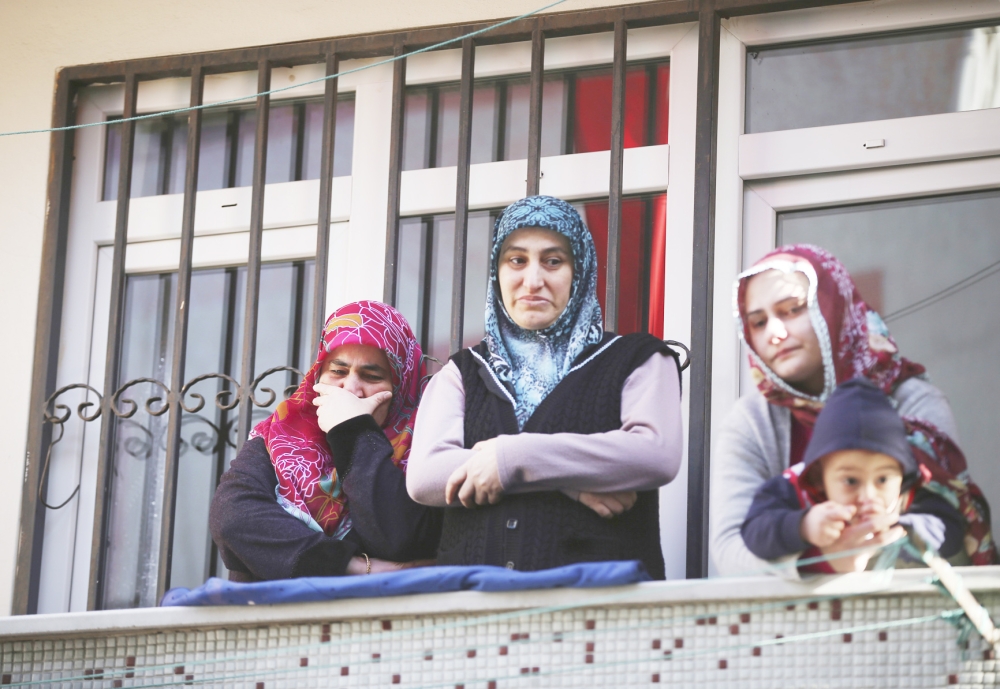 People watch from a balcony during the funeral processions for Fatih Cakmak, one of the victims of the attack at a nightclub on New Year's Day, in Istanbul, Monday, Jan. 2, 2017. Turkey's state-run news agency says police have detained eight people in connection with the Istanbul nightclub attack. The gunman, who escaped after carrying out the attack, wasn't among the eight. The Islamic State group has claimed responsibility for the attack, which killed 39 people, most of them foreigners. (AP Photo/Emrah Gurel)