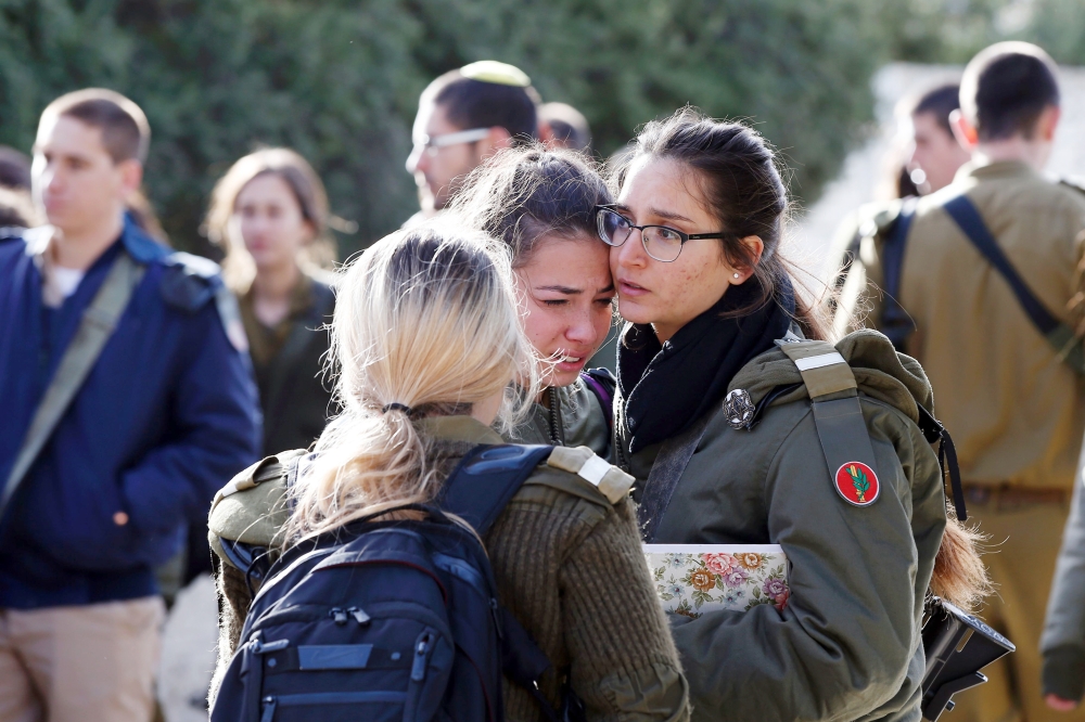 Israeli soldiers console each other at the site of a vehicle-ramming attack in Jerusalem on January 8, 2017. A truck ploughed into a group of soldiers in Jerusalem on in which a number of people were injured.

 / AFP / AHMAD GHARABLI
