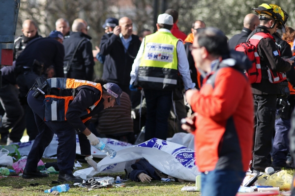 EDITORS NOTE: Graphic content / An Israeli police officer covers the body of a victim as Israeli security forces and emergency personnel gather at the site of a vehicle-ramming attack in Jerusalem on January 8, 2017. / AFP / MENAHEM KAHANA
