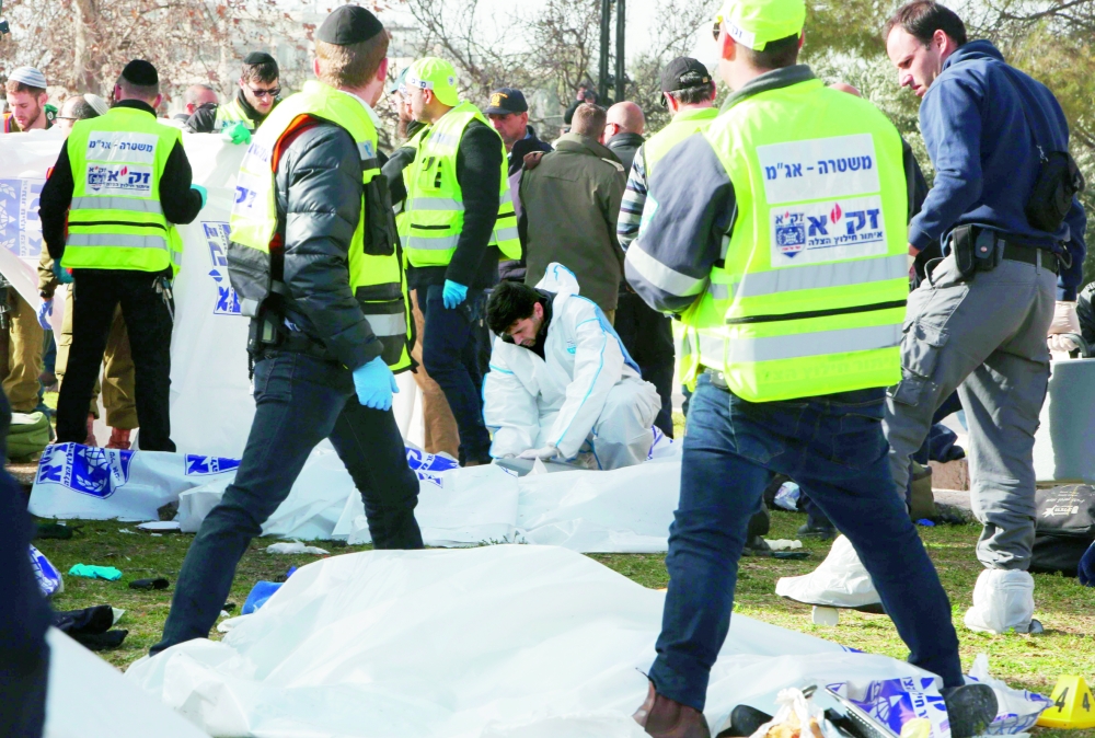 شرطة الاحتلال وخبراء الطب الشرعي يفحصون جثة أحد الجنود القتلى أمس. (ا ف ب) 
