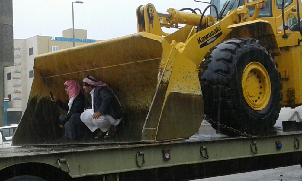 





مواطنان في حي المنسك بأبها يحتميان من المطر داخل «جرافة» لالتقاط صور للأمطار.  (تصوير: يحيى الفيفي)