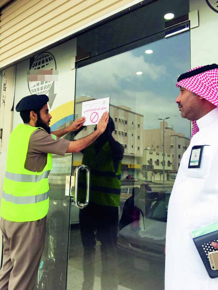 الدفاع المدني خلال إغلاق إحدى المؤسسات المخالفة. (عكاظ)