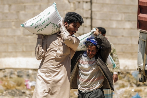 Displaced Yemenis carries sacks of food supplies, distributed by the Russian humanitarian relief mission at a camp on the outskirts of the capital Sanaa on March 16, 2017. / AFP / MOHAMMED HUWAIS
