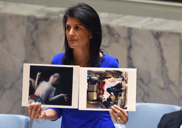 TOPSHOT - US Ambassador to the UN, Nikki Haley holds photos of victims as she speaks as the UN Security Council meets in an emergency session at the UN on April 5, 2017, about the suspected deadly chemical attack that killed civilians, including children, in Syria. / AFP / TIMOTHY A. CLARY
