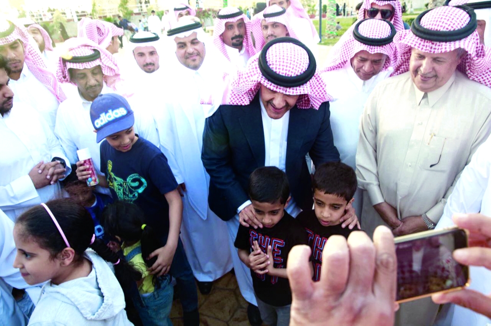 الأمير سلطان بن سلمان محتضناً أطفالاً في المهرجان. (عكاظ)