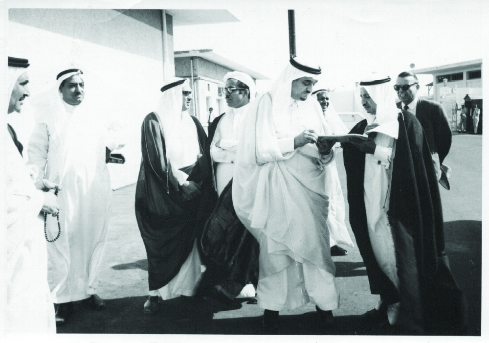في مطار جدة القديم يوقع الملك فهد بن عبدالعزيز على بعض الأوراق العاجلة مع عبدالله الجفري رئيس بلدية جدة ويبدو خياط في الخلف.