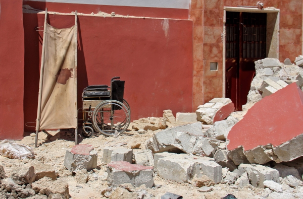 TOPSHOT - A wheelchair is seen amidst debris following air strikes on the rebel-held village of Kafr Tekharim in northwest Syria early on April 25, 2017 in which 12 people were killed 12 people and put a nearby field clinic out of service.  / AFP / Omar haj kadour
