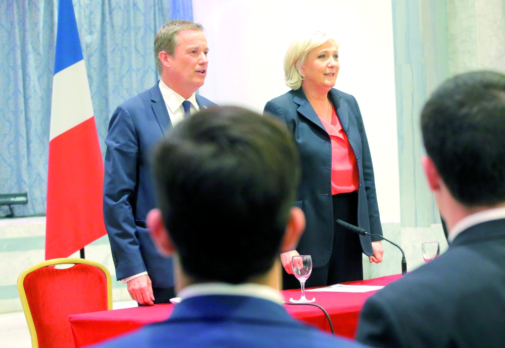 New campaign ally Nicolas Dupont-Aignan, left, and far-right candidate for the 2017 French presidential election Marine Le Pen sing the national anthem during media conference in Paris, France, Saturday, April 29, 2017. Far-right candidate Marine Le Pen says her new campaign ally, Nicolas Dupont-Aignan, would be her prime minister if she is elected. (AP Photo/Michel Euler)