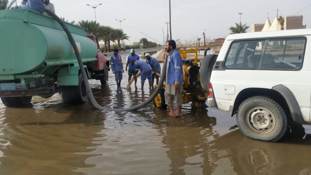 عمال تابعون لبلدية بيشة خلال شفط مياه الأمطار.