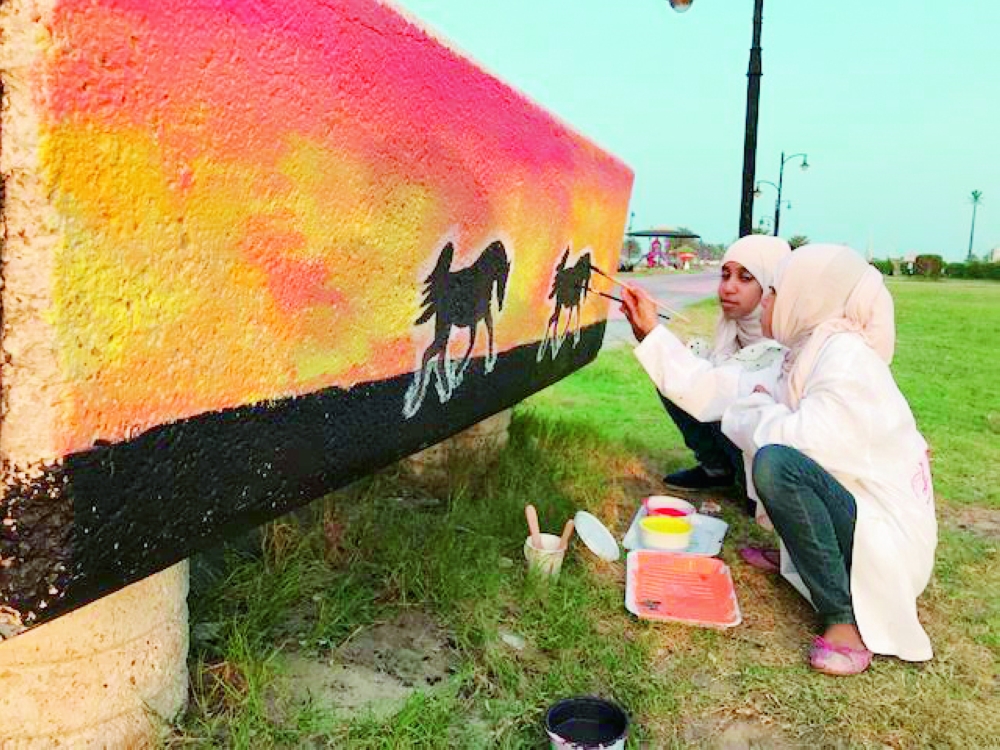 فتاتان أثناء رسم لوحة على أحد الجدران.