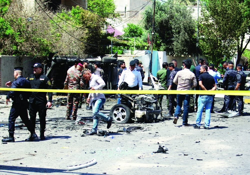 آثار التفجير الذي وقع في بغداد أمس، وفي الإطار سيارتان تعرضتا للتدمير جراء التفجير. (أ. ف. ب)  