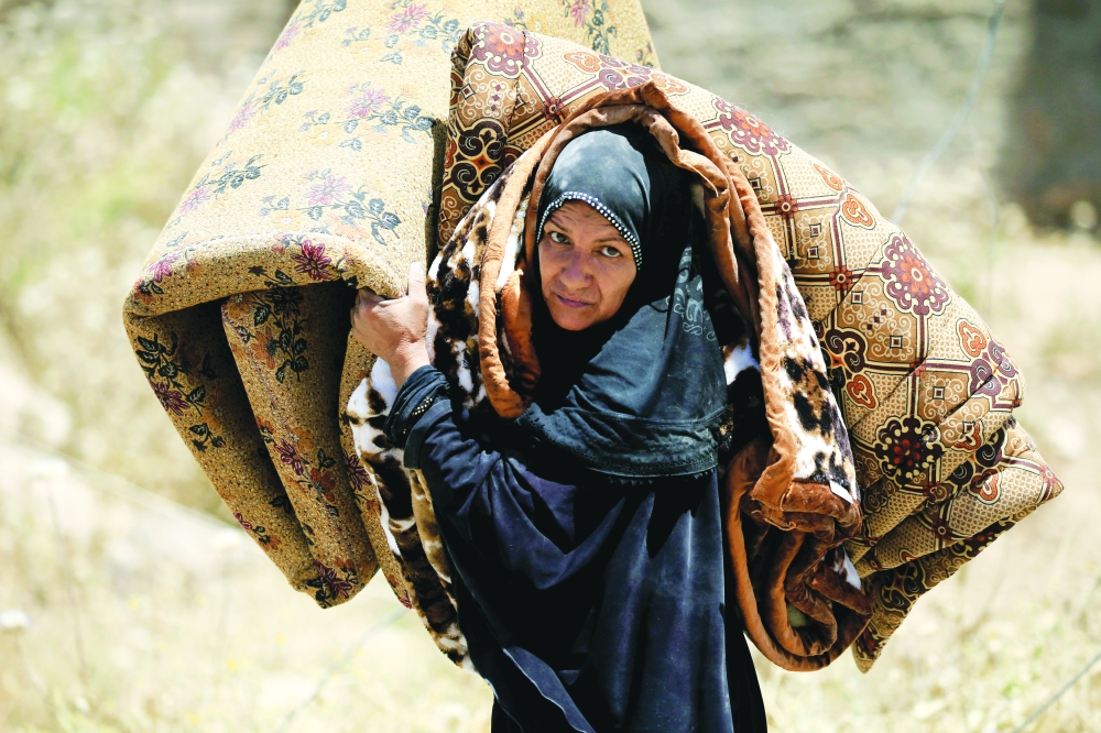 عراقية نازحة من جنوب الموصل تحمل أمتعتها.  (رويترز)