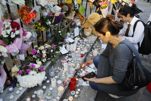 Wellwishers light candles for those who died in the fire that gutted Grenfell Tower, a residential tower block in west London on June 14. Dozens of people are feared dead in the London tower block fire as emergency workers continued searching for bodies in the high-rise on Friday, warning they may never be able to identify some of the victims. / AFP / Tolga AKMEN
