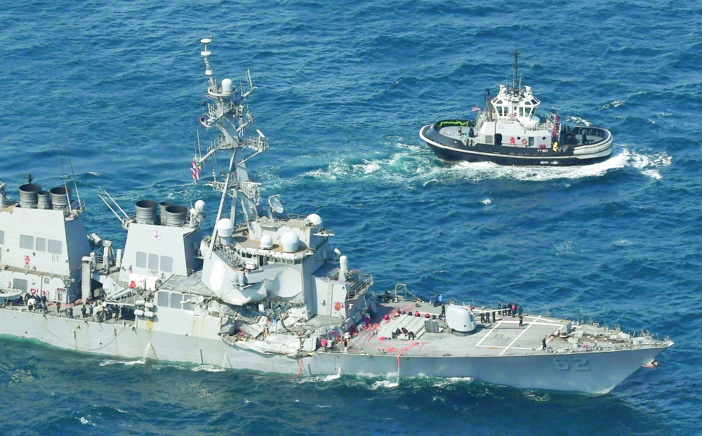 The USS Fitzgerald, left, heads to Yokosuka, home base of the 7th Fleet,  beside a U.S. tugboat, off Shimoda, Shizuoka prefecture, Japan, after the Navy destroyer collided with a merchant ship, Saturday,  June 17, 2017.  The U.S. Navy says the USS Fitzgerald suffered damage below the water line on its starboard side after it collided with a Philippine-flagged merchant ship.  (Iori Sagisawa/Kyodo News via AP)