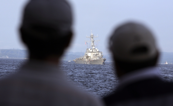 People watch the damaged USS Fitzgerald being towed near the U.S. Naval base in Yokosuka, southwest of Tokyo, after the U.S. destroyer collided with the Philippine-registered container ship ACX Crystal in the waters off the Izu Peninsula Saturday, June 17, 2017. Crew members from the destroyer USS Dewey were helping stabilize the damaged USS Fitzgerald after its collision off the coast of Japan before dawn Saturday, leaving seven sailors missing and at least three injured. (AP Photo/Eugene Hoshiko)