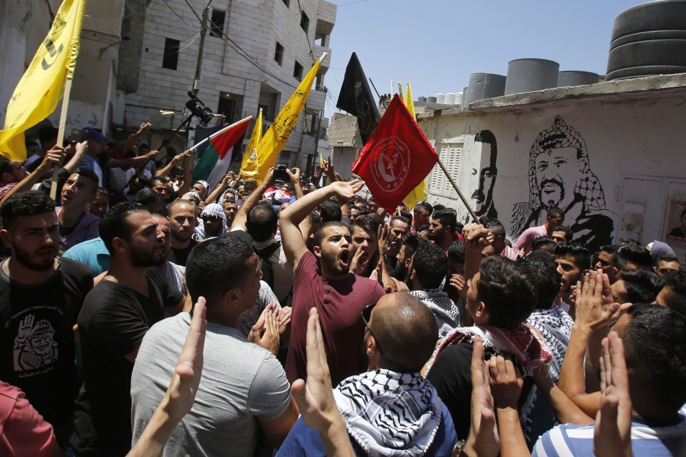 A Palestinian mourner shouts slogans as others carry the body of Palestinian Bara Hamamdah, who was shot dead during clashes with Israeli forces, during his funeral at the Dheisheh Refugee Camp, near the West Bank town of Bethlehem, on July 14, 2017.  A Palestinian was killed during clashes with Israeli forces at a refugee camp near the city of Bethlehem in the occupied West Bank, the Palestinian health ministry said. / AFP / Musa AL SHAER
