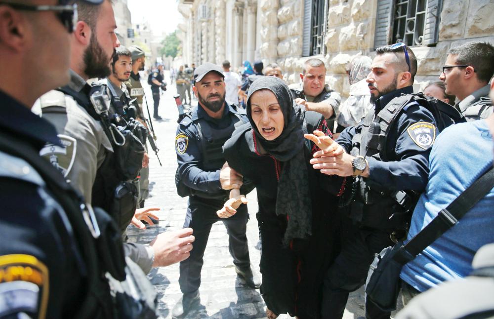 جنود الاحتلال يعتقلون فلسطينية خلال مظاهرة أمام المدخل الرئيسي لمجمع المسجد الأقصى أمس. (أ. ف. ب)