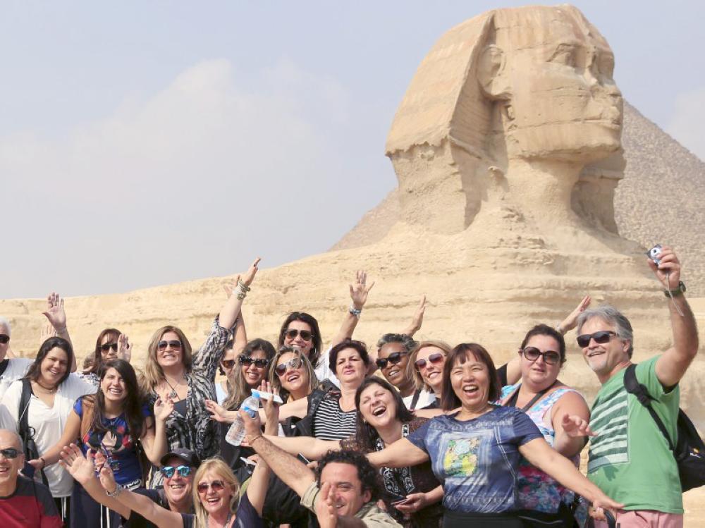 Tourists smile and cheer as they take a souvenir photo in front of the Sphinx at the Giza Pyramids on the outskirts of Cairo, Egypt, November 8, 2015. Egypt's Tourism Minister Hesham Zaazou said Cairo regretted the suspension of flights and was doing all it could to secure its airports and tourist sites, adding that he would fly to Sharm al-Sheikh to oversee measures to support tourists there. REUTERS/Amr Abdallah Dalsh