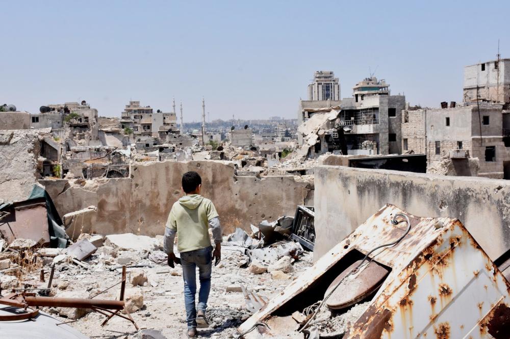 (FILES) This file photo taken on July 22, 2017 shows a Syrian boy walking amid the rubble of destroyed buildings, in the northern city of Aleppo, which was recaptured by government forces in December 2016. A UN commission probing Syria rights abuses has gathered enough evidence to convict President Bashar al-Assad of war crimes, an outgoing member of the commission said in interviews published on August 13, 2017. Veteran former war crimes prosecutor Carla Del Ponte, who is preparing to step down after five years serving in the UN Commission of Inquiry on Syria, told Swiss media the evidence against Assad was sufficient to secure a war crimes conviction. / AFP / George OURFALIAN
