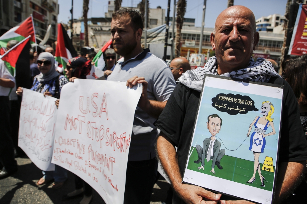 A picture taken on August 24, 2017 in the West Bank city of Ramallah shows Palestinian demonstrators holding a cartoon depicting Senior White House Advisor Jared Kushner along with other slogans protesting against the arrival of a US delegation headed by Kushner to meet with Palestinian president Mahmoud Abbas. / AFP / ABBAS MOMANI
