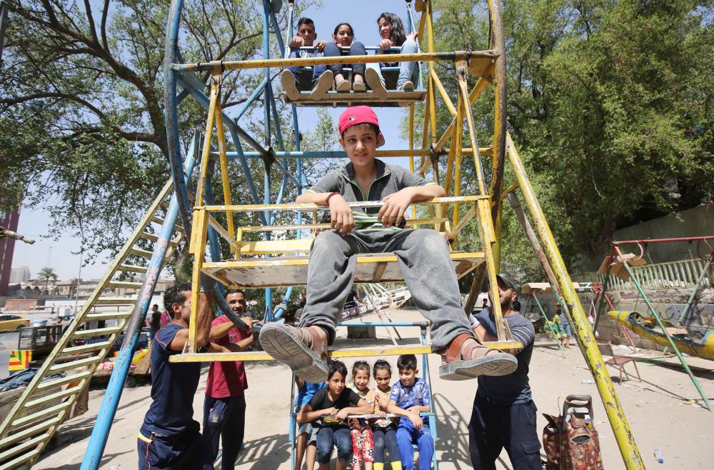 Iraqi children play in an amusement park on the second day of Eid al-Adha, or the Festival of Sacrifice, in a park in central Baghdad on September 2, 2017. Muslims around the world are preparing to celebrate the Eid al-Adha feast, set for 01 September 2017, when they will slaughter cattle, goats and sheep in commemoration of the Prophet Abraham's readiness to sacrifice his son to show obedience to God. / AFP / Ahmad al-Rubaye
