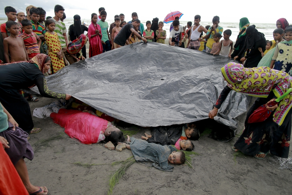 In this Thursday, Aug. 31, 2017, file photo, Bangladeshi villagers cover bodies of Rohingya women and children at Shah Porir Deep, in Teknak, Bangladesh. Three boats carrying ethnic Rohingya fleeing violence in Myanmar have capsized in Bangladesh and over two dozen bodies of women and children have been recovered, officials said Thursday. (AP Photo/Suvra Kanti Das, File)