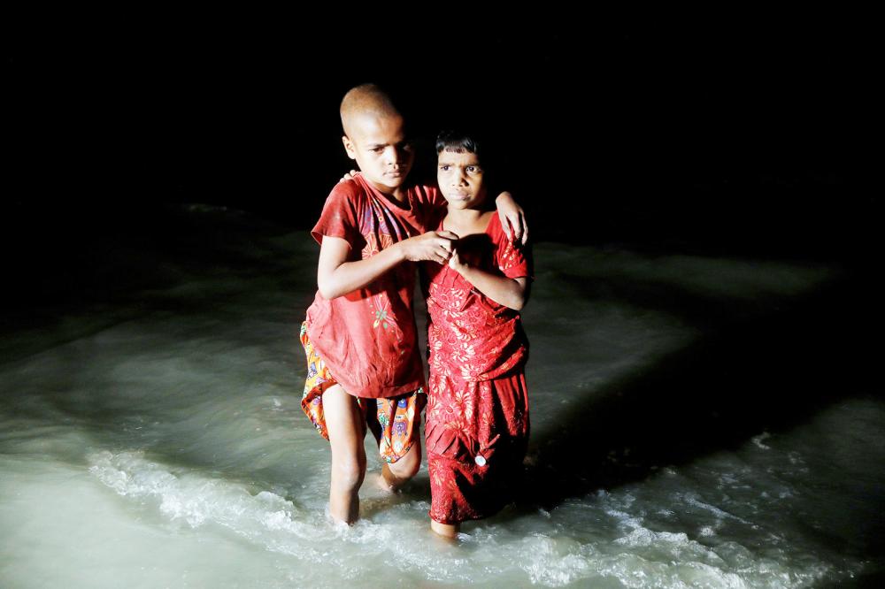 Rohingya refugee sisters, who just arrived under the cover of darkness by wooden boats from Myanmar, hug each other as they try to find their parents at Shah Porir Dwip, in Teknaf, near Cox's Bazar in Bangladesh, September 29, 2017. Picture taken September 29, 2017. REUTERS/Damir Sagolj TPX IMAGES OF THE DAY