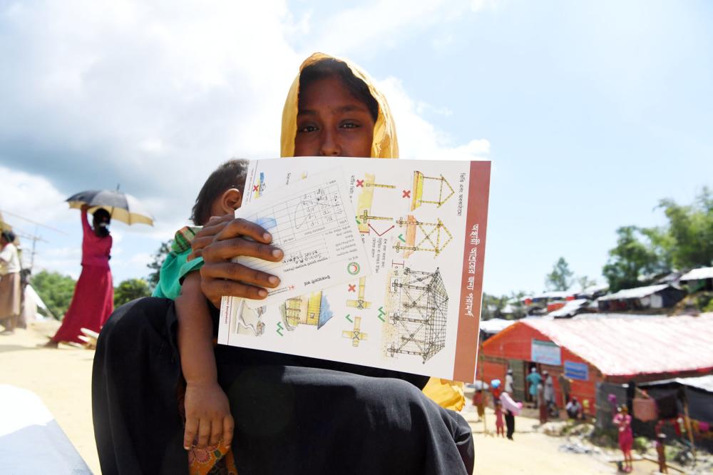 Rohingya refugee woman waits for her husband after collecting health and sanitation aid at the the Balukhali refugee camp in the Bangladeshi district of Ukhia on October 14, 2017. Bangladesh's home minister said on October 12 he will travel to Myanmar on October 23 for talks on the crisis that has seen more than half a million Rohingya refugees cross into his country in just six weeks. / AFP / INDRANIL MUKHERJEE
