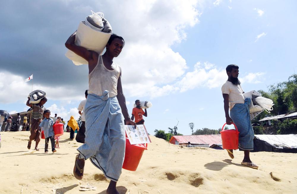 Rohingya refugees walk back after collecting health and sanitation aid at the Balukhali refugee camp in the Bangladeshi district of Ukhia on October 14, 2017. Bangladesh's home minister said on October 12 he will travel to Myanmar on October 23 for talks on the crisis that has seen more than half a million Rohingya refugees cross into his country in just six weeks. / AFP / INDRANIL MUKHERJEE
