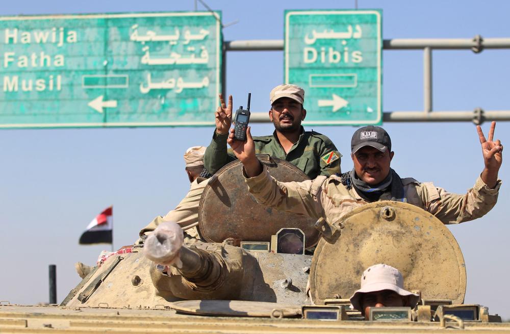 Iraqi forces flash the sign for victory as they advance in the southern outskirts of Kirkuk towards the city during an operation against Kurdish fighters on October 16, 2017.  Iraqi forces clashed with Kurdish fighters near the disputed city of Kirkuk, seizing a key military base and other territory in a major operation sparked by a controversial independence referendum. / AFP / AHMAD AL-RUBAYE
