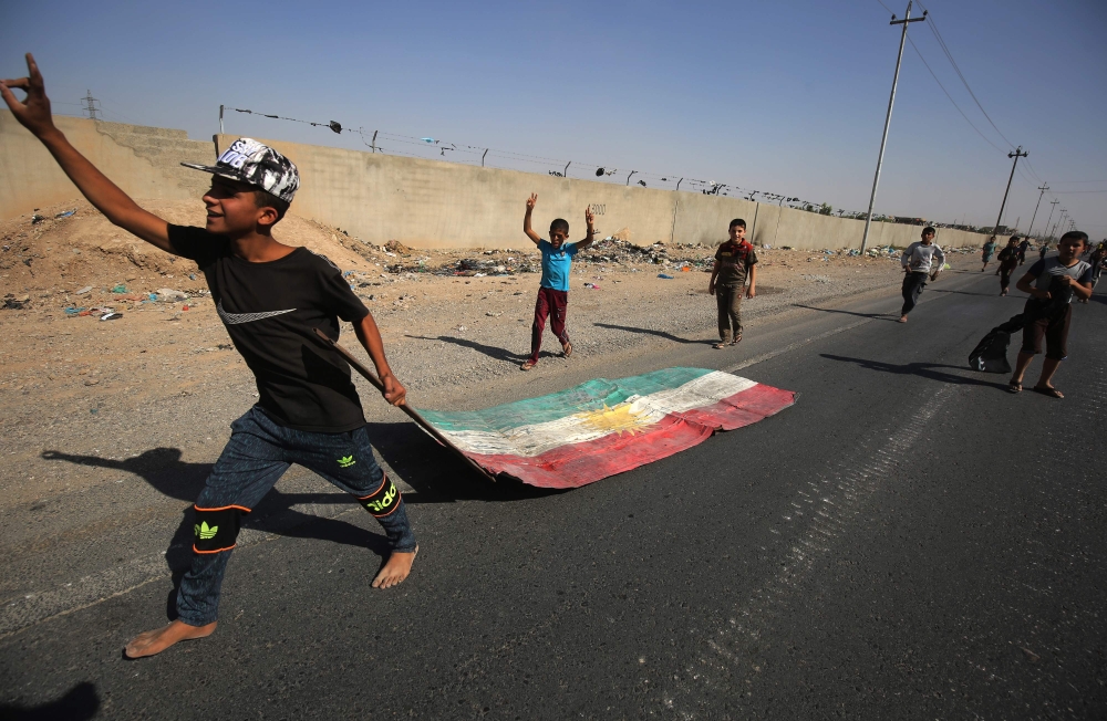 TOPSHOT - An Iraqi boy drags a Kurdish flag as Iraqi forces advance towards the centre of Kirkuk during an operation against Kurdish fighters on October 16, 2017. Iraqi forces seized the Kirkuk governor's office, key military sites and an oil field as they swept across the disputed province following soaring tensions over an independence referendum. / AFP / AHMAD AL-RUBAYE
