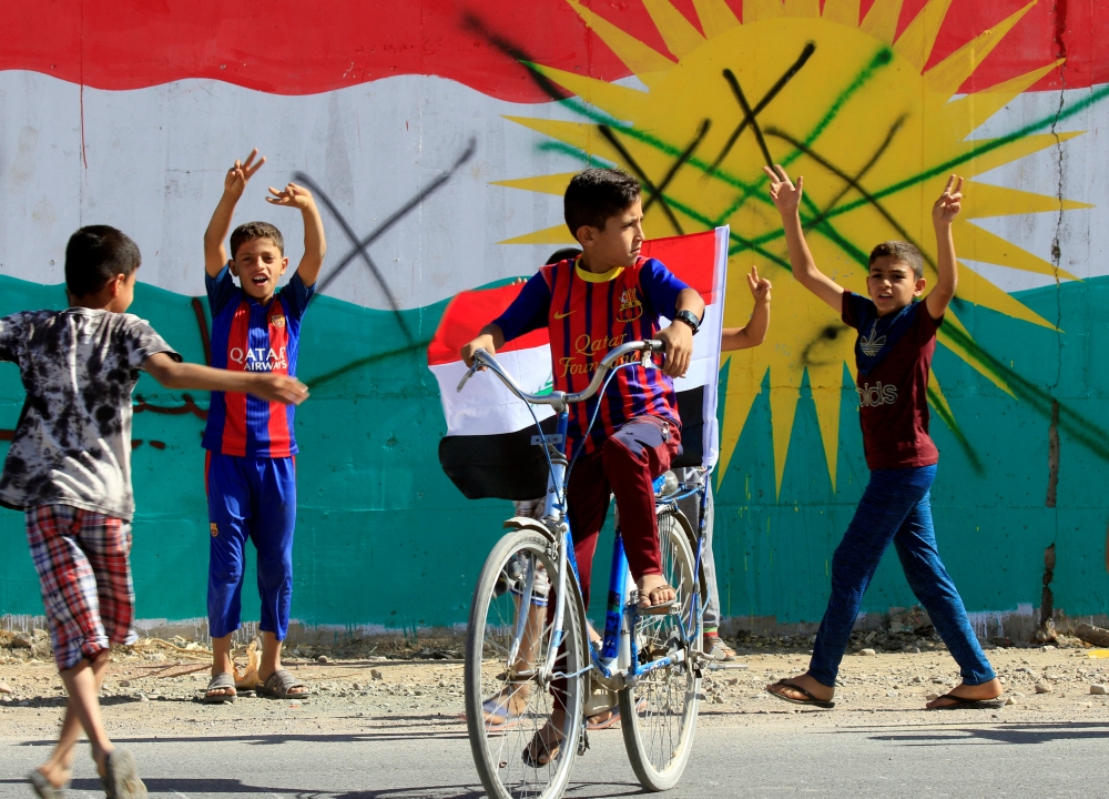 A boy drives a bicycle with an Iraqi flag in Dibis area on the outskirts of Kirkuk, Iraq October 17, 2017. REUTERS/Alaa Al-Marjani