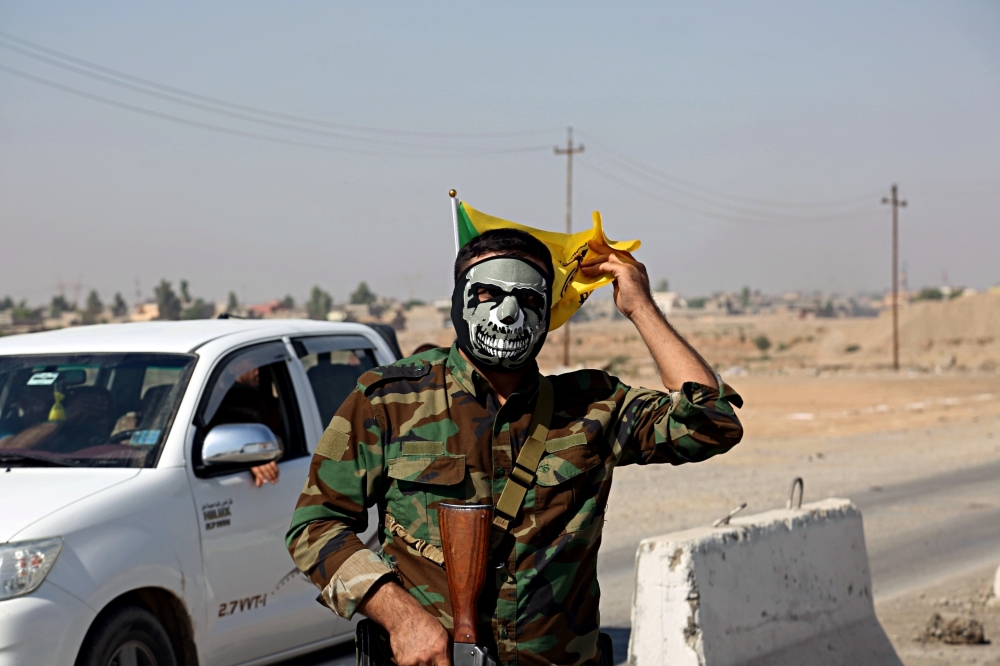 A fighter with Popular Mobilization Forces stands guard in Tuz Khormato, that was evacuated by Kurdish security forces, 130 miles (210 kilometers) north of Baghdad, Iraq, Monday, Oct. 16, 2017. Two weeks after fighting together against the Islamic State, Iraqi forces pushed their Kurdish allies out of the disputed city of Kirkuk on Monday, seizing oil fields and other facilities amid soaring tensions over last month's Kurdish vote for independence. (AP Photo)