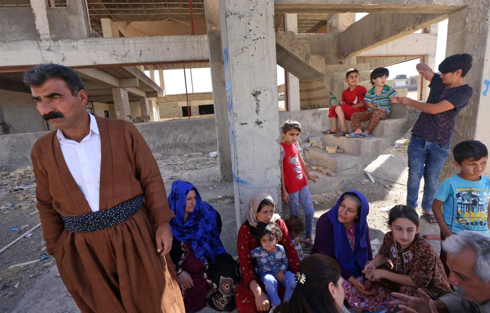 Displaced Iraqi Kurdish people fleeing violence in the northern Kirkuk province sit an unfinished housing project where they are taking shelter in Arbil, the capital of the autonomous Kurdish region of northern Iraq, on October 19, 2017. / AFP / SAFIN HAMED
