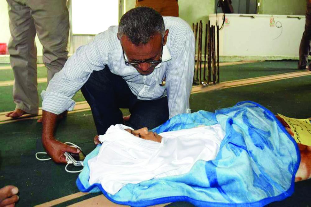 يمني يلقي النظرة الأخيرة على طفله الذي قتل بقذائف الميليشيات في تعز.(متداولة)