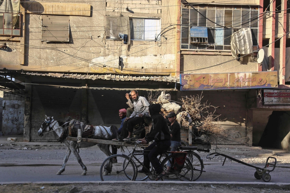 TOPSHOT - A Syrian man transports wood in a horse cart in Douma, a rebel-held town on the outskirts of the capital Damascus, on October 24, 2017. 

 According to the World Bank, the conflict in Syria has cost the country's economy some $226 billion -- about four times the country's gross domestic product in 2010. The fighting has damaged or destroyed 27 percent of Syria's housing stock and about half the country's medical and educational facilities. About 85 percent of the population lives below the poverty line and half are unemployed. 
 / AFP / Amer ALMOHIBANY
